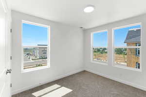 Carpeted spare room featuring baseboards