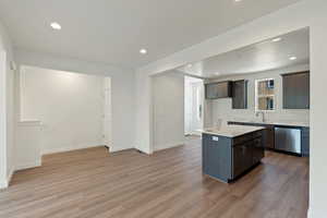 Kitchen with light countertops, recessed lighting, stainless steel dishwasher, light wood-style flooring, and a center island