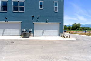 Exterior space featuring an attached garage, a mountain view, stucco siding, and concrete driveway