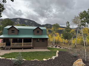 View of front of home featuring a mountain view, a front yard, a porch, and log exterior