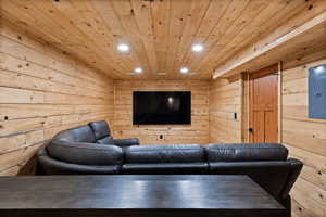 Living area with wooden walls, recessed lighting, wooden ceiling, and electric panel