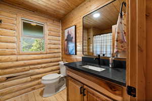 Full bathroom featuring vanity, log walls, wooden ceiling, and hardwood / wood-style flooring