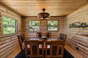 Dining space with healthy amount of natural light, rustic walls, and wood ceiling