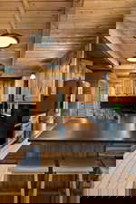 Kitchen with a wooden ceiling with exposed beams, dark countertops, range, a peninsula, and a breakfast bar area