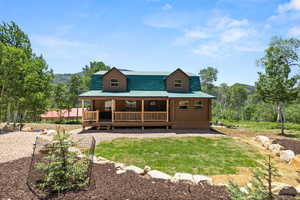 Rear view of property with covered porch, a yard, log exterior, and a mountain view