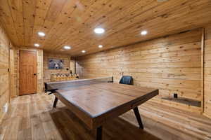 Playroom with wood walls, recessed lighting, light wood finished floors, and wood ceiling