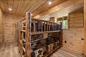 Bedroom featuring wooden walls, wood-type flooring, recessed lighting, and wood ceiling