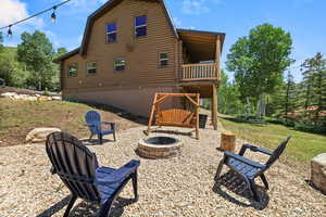 Back of property featuring an outdoor fire pit, a gambrel roof, and log siding