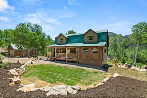 Back of property featuring an outdoor fire pit, a porch, log exterior, an outdoor structure, and a garage