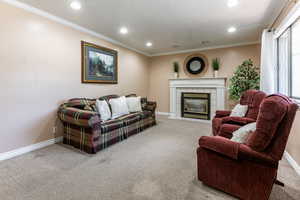 Living room with carpet floors, recessed lighting, ornamental molding, and a tiled fireplace