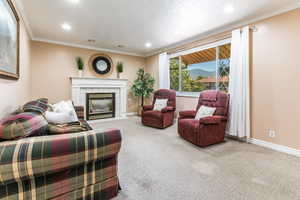 Carpeted living area featuring recessed lighting, a tile fireplace, and ornamental molding