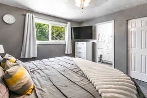 Primary bedroom featuring a textured ceiling, ensuite bath, and carpet floors
