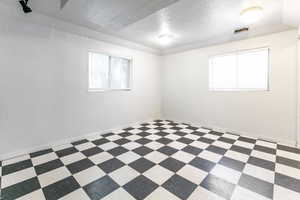 Bedroom featuring plenty of natural light, a textured ceiling, a textured wall, and vinyl patterned floors