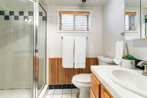 Bathroom featuring vanity, a shower stall, tile patterned floors, and a wainscoted wall