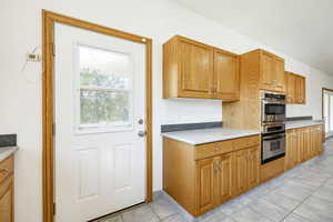Kitchen featuring stainless steel double oven, light tile patterned floors, light countertops, and brown cabinetry