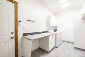 Laundry area with cabinet space, washing machine and clothes dryer, and light tile patterned flooring