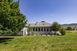 Rear view of property with a lawn and roof with shingles