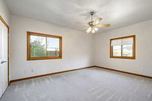 Carpeted empty room with baseboards and a ceiling fan