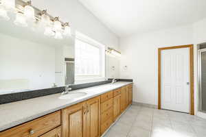 Full bath with a shower stall, double vanity, and tile patterned flooring