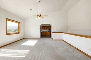 Unfurnished living room with light colored carpet, vaulted ceiling, and ceiling fan