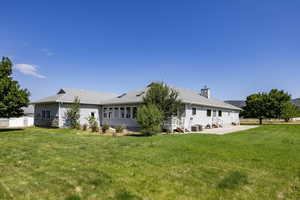 Back of property with a lawn, a chimney, and a patio