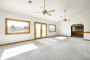 Spare room featuring light colored carpet, a ceiling fan, arched walkways, and high vaulted ceiling