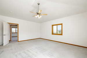Empty room featuring light colored carpet and a ceiling fan