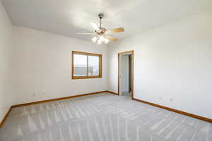 Empty room featuring light carpet and a ceiling fan