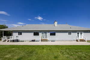 Rear view of property with entry steps, a shingled roof, a yard, and a chimney
