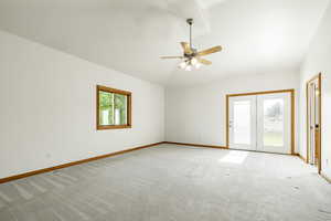 Empty room with lofted ceiling, light carpet, and ceiling fan