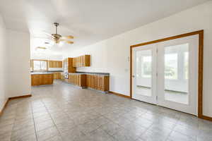 Kitchen featuring brown cabinetry, light countertops, light tile patterned floors, and a ceiling fan
