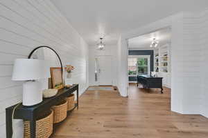Entryway featuring a chandelier, light wood finished floors, and wooden walls