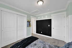 Bedroom with carpet, attic access, ornamental molding, and a closet