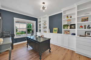 Office featuring light wood-style floors, built in features, crown molding, and a chandelier