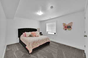 Carpeted bedroom with baseboards and a textured ceiling