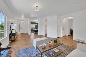 Living area featuring arched walkways, light wood-type flooring, and a chandelier