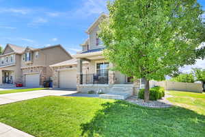 View of front of home with stucco siding, driveway, a porch, stone siding, and an attached garage