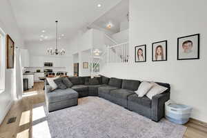 Living area with stairs, light wood-style floors, a chandelier, high vaulted ceiling, and recessed lighting