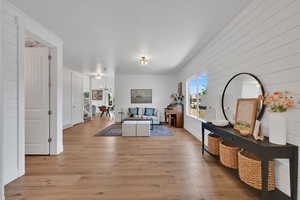Living room with a chandelier, light wood finished floors, and wood walls