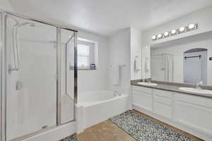 Full bath featuring a stall shower, double vanity, a bath, and tile patterned floors