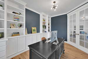 Office area with ornamental molding, french doors, light wood-style flooring, and a chandelier