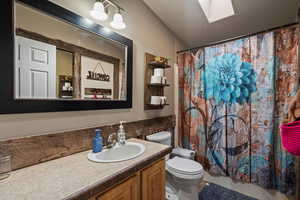Full bath with vanity, curtained shower, and a skylight