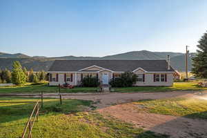 Ranch-style home with a mountain view, a front lawn, and driveway
