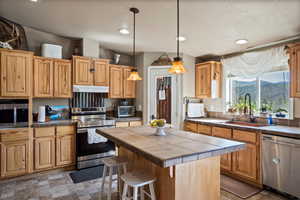 Kitchen featuring appliances with stainless steel finishes, under cabinet range hood, a mountain view, a kitchen island, and recessed lighting