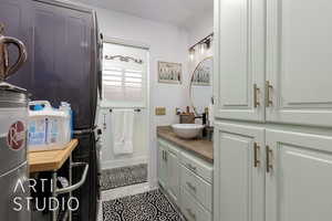 Bathroom with stacked washer and clothes dryer, vanity, and tile patterned floors