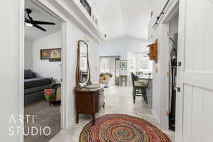 Foyer featuring vaulted ceiling, a barn door, ceiling fan, and light marble finish flooring
