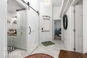 Foyer entrance featuring a barn door and light marble finish floors