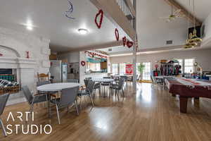 Dining room with light wood-type flooring, a ceiling fan, a multi sided fireplace, beamed ceiling, and pool table