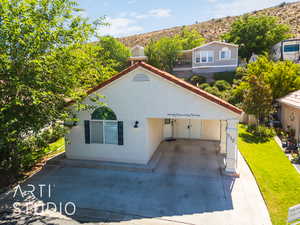 Back of house with stucco siding, a mountain view, and a lawn