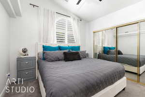 Bedroom with carpet, multiple windows, a closet, and lofted ceiling